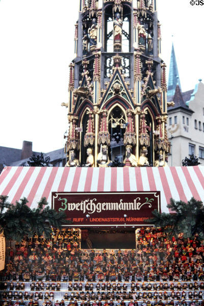 Booth of figurines made from prunes in front of Schöner Brunnen (beautiful fountain) at Christmas Market on Frauen Kirche square. Nuremberg, Germany.