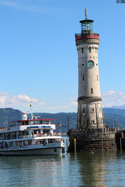 Sightseeing boat passing lighthouse (1856) at harbor entrance. Lindau im Bodensee, Germany.