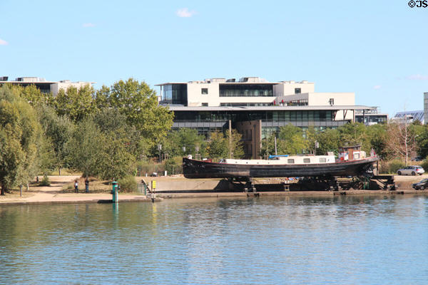 Beached barge on shore of Rhône River opposite Musée des Confluences. Lyon, France.