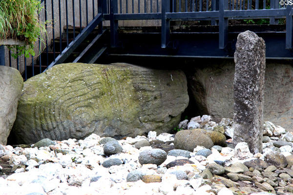 Spiral carved stones & standing stone marking entrance of Main Neolithic passage grave (c3200 BCE) at Knowth. Ireland.