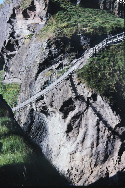Carrick-a-rede Rope Bridge casts shadow on cliffs below. Northern Ireland.