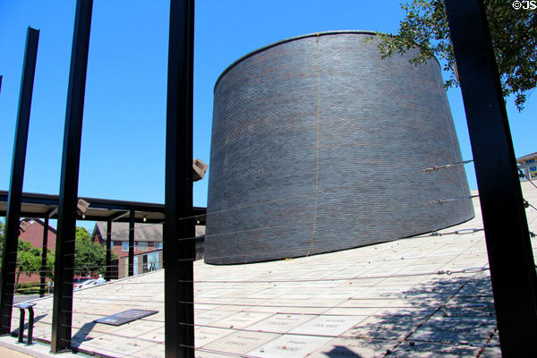 Sloped front with names ringed with wire fence & topped with round chimney represents elements of concentration camps at Holocaust Museum Houston. Houston, TX.