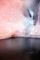 Red & blue stones of Uluru meet a pool of water. Australia.