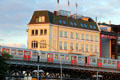 Subway train passes yellow building where Ditmar-Koel-Straße meets Elbe River. Hamburg, Germany.