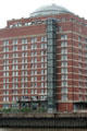 Modern brick residential building with glass dome & exterior elevator overlooking Elbe River in Altona borough. Hamburg, Germany.