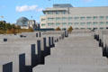 Array of slabs of Monument to Murdered Jews of Europe with Bundestag federal parliament dome beyond. Berlin, Germany