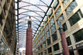 Pair of modern buildings spanned by glass-roofed gallery with statues atop columns. Berlin, Germany.