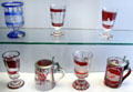 Collection of glass goblets & steins where outer colored layer is cut away to form silhouette decorative souvenir pictures of northern Germany at Schleswig Holstein State Museum. Schleswig, Germany.