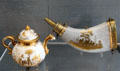 Meissen porcelain teapot with eagle spout plus powder horn both gilded with Chinese scenes at Meissen porcelain museum at Lustheim Palace. Munich, Germany.