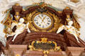 Ornate gilded clock with statues of angels escaping their space at St Benedict church above alter at Benediktbeuern Abbey. Germany.