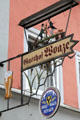 Ornate metal work of two men in top hats & dog hanging from Brau Haus Füssen. Füssen, Germany.