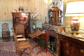 Fireplace with mantle clock flanked by desks, chairs & cabinet in birth chamber at Cheverny Chateau. Cheverny, France.