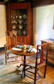 Round tea table with chairs before corner china cabinet at Stanley-Whitman House. Farmington, CT.