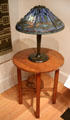 Stained glass dragonfly table lamp by Louis Comfort Tiffany of New York on round table by Gustav Stickley made by Craftsman Workshops of Eastwood, NY at Yale University Art Gallery. New Haven, CT.