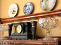 Mantle clock, glass footed bowls & commemorative plates in Staiti House at Sam Houston Park. Houston, TX.