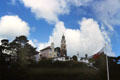 View of Portmeirion Village atop hill with Welsh flag in foreground. Gwynedd, Wales.