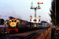 Cargo train pulls into rail station passing old Dutch church. Jogyakarta, Indonesia.